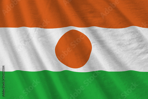 Niger flag with big folds waving close up under the studio light indoors. The official symbols and colors in fabric banner photo