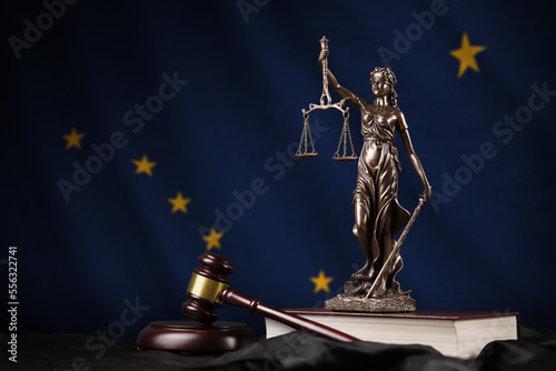 Alaska US state flag with statue of lady justice, constitution and judge hammer on black drapery. Concept of judgement and punishment photo