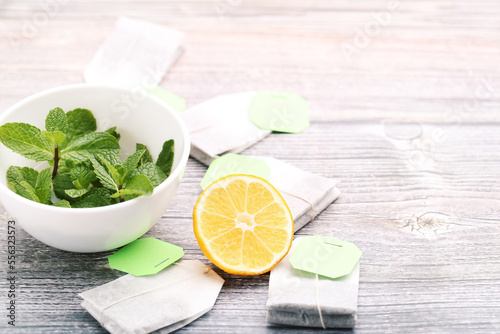 Tea bags with lemon and mint leafs on wooden table