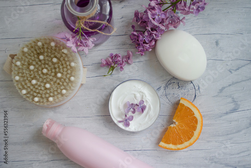 Massage brush, cream, lilac flower, orange on a light background