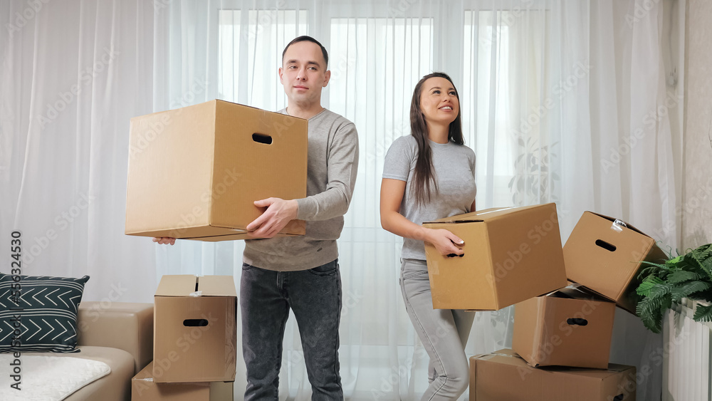 Husband and wife unpack boxes to prepare new apartment for arrangement and decoration. Married couple enjoys moving into new property together Husband and wife unpack boxes to prepare new apartment for arrangement and decoration. Married couple enjoys moving into new property together
