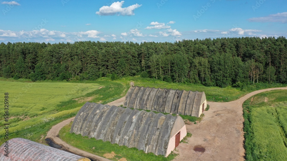 Old soviet abandoned military hangar in the forest for storing short-range missiles, military equipment, ammunition, equipment. Gray hangar with rusty metal door Old soviet abandoned military hangar in the forest for storing short-range missiles, military equipment, ammunition, equipment. Gray hangar with rusty metal door