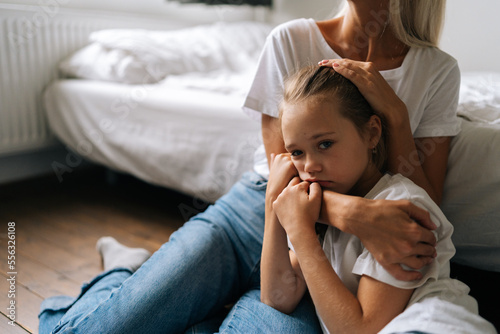 Obraz na plátne Portrait of sad little girl looking at camera and loving caring mother comforting offended afraid child daughter, showing love and care, expressing support, hugging and stroking hair sitting on floor
