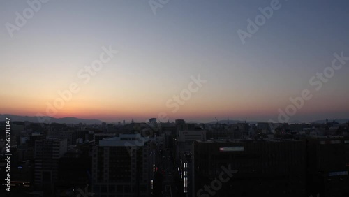 HAKATA, FUKUOKA, JAPAN - NOVEMBER 2022 : Aerial high angle time lapse shot of Fukuoka city in sunset. View of Tenjin and Nakasu downtown area from Hakata station. photo