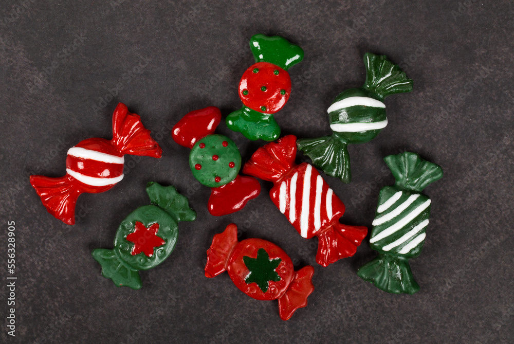 Christmas candies. Themed cute sweets covered with colored icing sugar. Dark gray background. Top view. Christmas candies. Themed cute sweets covered with colored icing sugar. Dark gray background. Top view.