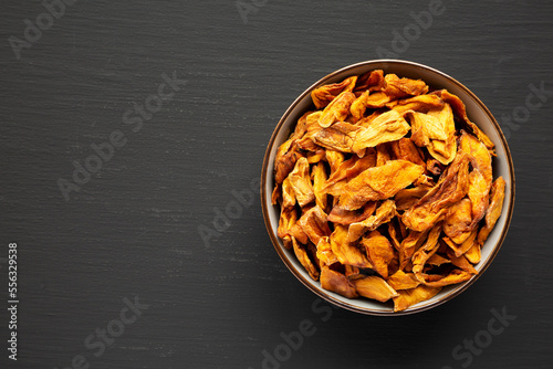Delicious Organic Dried Mango Fruit in a Bowl on a black background, top view. Flat lay, overhead, from above. Copy space.