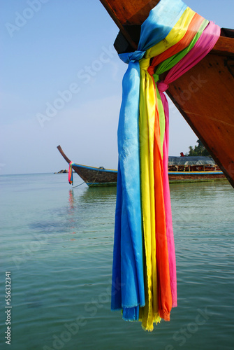 Wooden boats with colourful rainbow textile bands on the coast of Koh Lipe island in Thailand, a sunny relaxing day