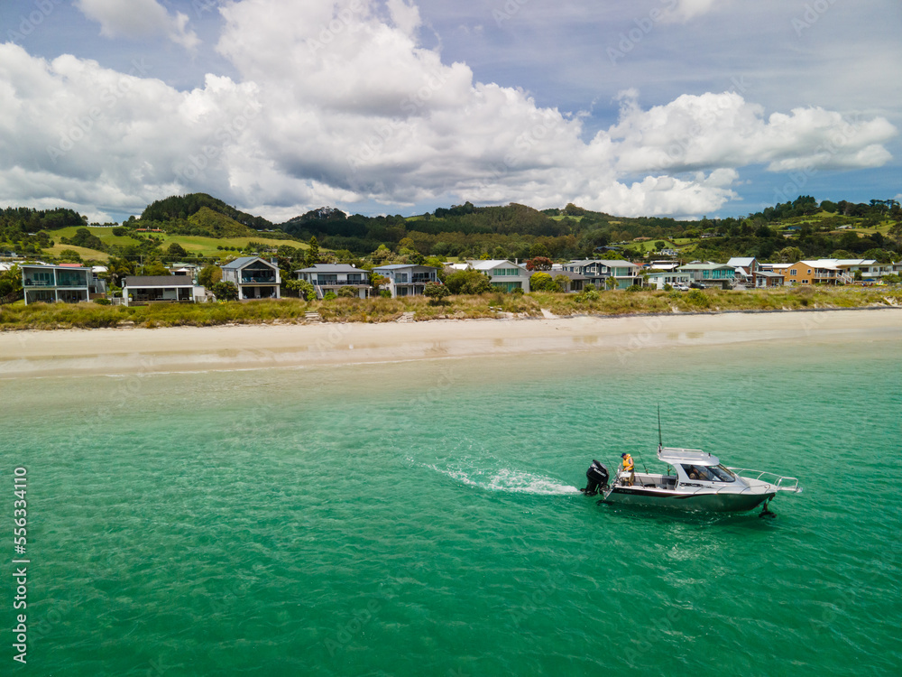 Amphibious fishing boat with Sea Legs driving from beach out to sea along New Zealand coastal town in the Coromandel Peninsula