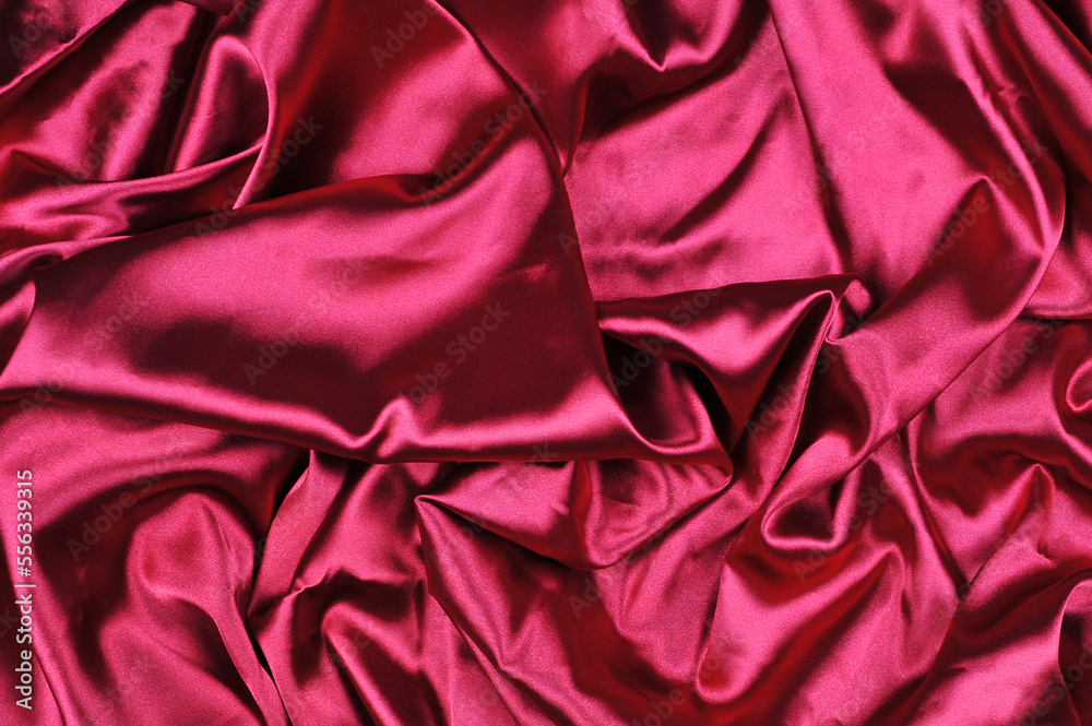 Magenta color silk waves texture background. Burgundy raspberry satin with color shine background. Top view. Magenta color silk waves texture background. Burgundy raspberry satin with color shine background. Top view.