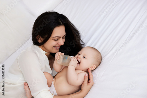 Slika na platnu happy mother feeding her newborn baby on the bed