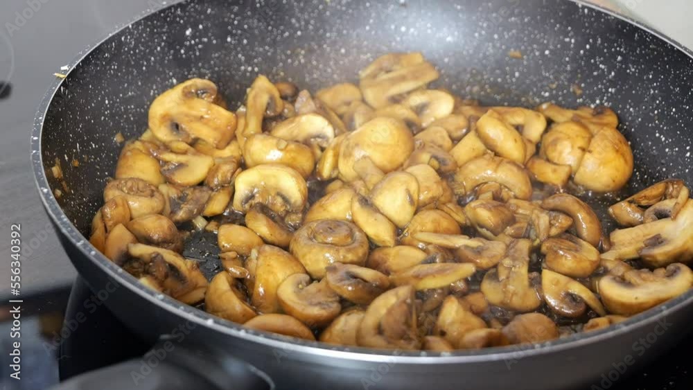 Close-up of chopped mushrooms, champignons are fried in soy sauce in a frying pan at home. Smoke over mushrooms. Close-up of chopped mushrooms, champignons are fried in soy sauce in a frying pan at home. Smoke over mushrooms.