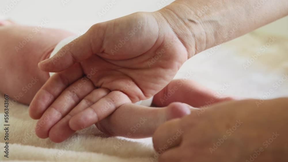 Hands of therapist rubs the small leg of infant. Masseur massaging little baby's foot. Happy infant girl doing baby massage by his mother at home. Newborn child about 2-5 months old. Hands of therapist rubs the small leg of infant. Masseur massaging little baby's foot. Happy infant girl doing baby massage by his mother at home. Newborn child about 2-5 months old.