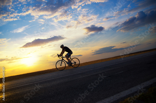 Young sports man cycling with bicycle on the road in summer