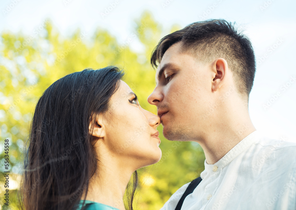 Young happy couple in love of different nationality hugging and kissing in the park. Asian woman and european man. Young happy couple in love of different nationality hugging and kissing in the park. Asian woman and european man.