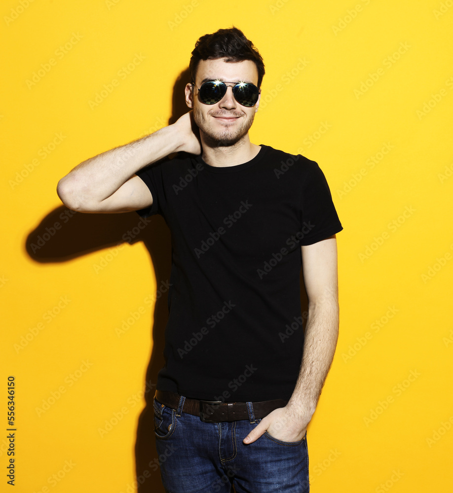 Young fashionable male model standing against yellow background Young fashionable male model standing against yellow background