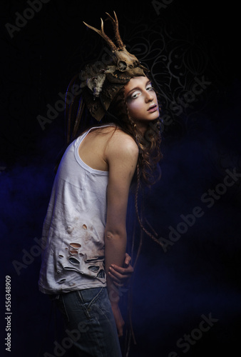 Beautiful young woman with bright make-up, braided hair and a skull on her head