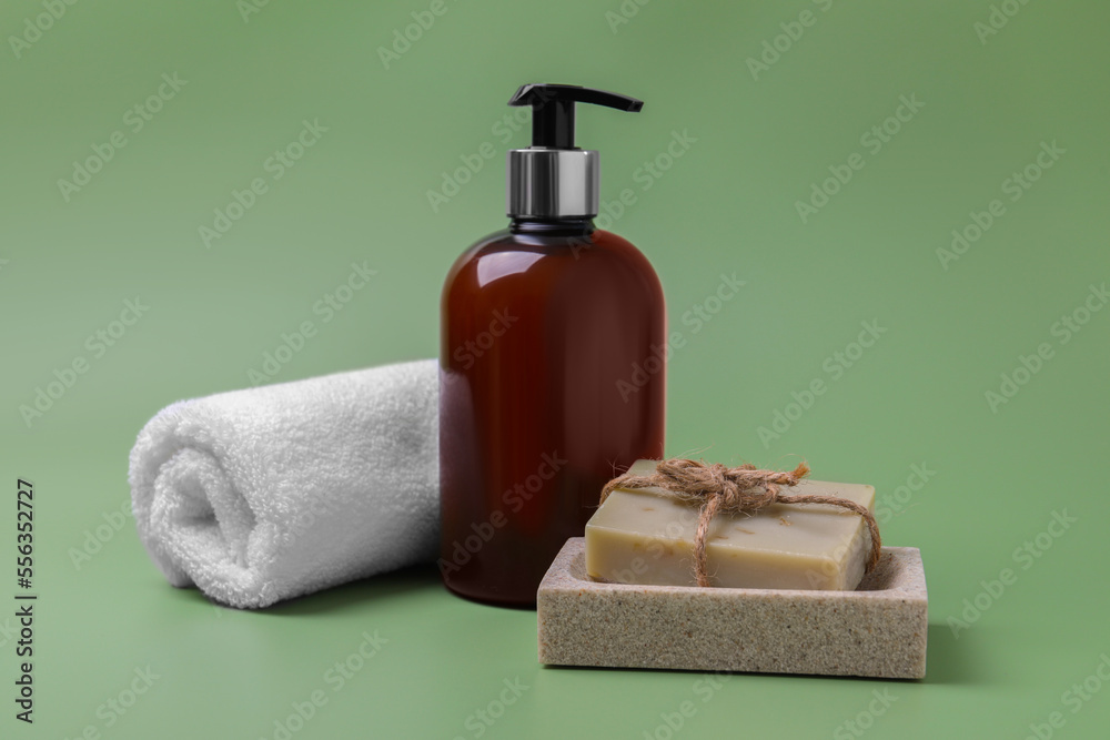 Soap bars, bottle dispenser and towel on green background Soap bars, bottle dispenser and towel on green background