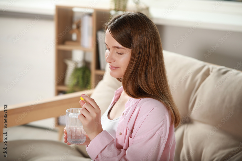 Beautiful pregnant woman holding pill and glass of water at home Beautiful pregnant woman holding pill and glass of water at home