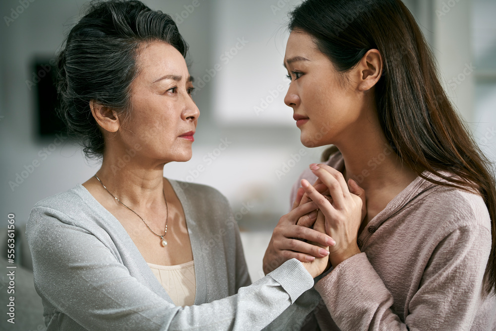 young asian daughter comforting elderly mother young asian daughter comforting elderly mother