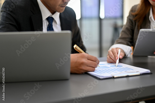 Smart Asian businessman working with a female accountant, checking financial data on the report