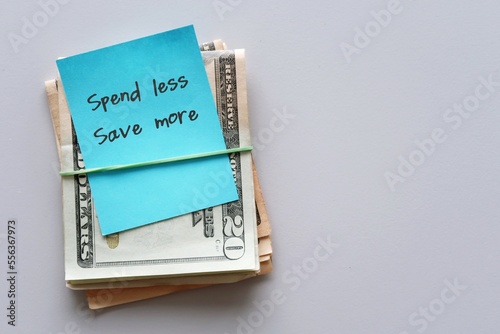 Dollars cash money on copy space background with handwritten text note SPEND LESS SAVE MORE, financial planning to achieve financial independence by spend less than earning