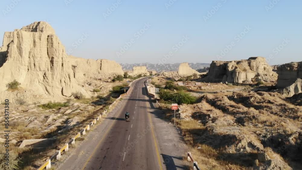 Aerial Tracking Shot Behind Motorbike Driving Along Empty Highway Road Through Hingol National Park In Balochistan Desert Landscape. Aerial Tracking Shot Behind Motorbike Driving Along Empty Highway Road Through Hingol National Park In Balochistan Desert Landscape.