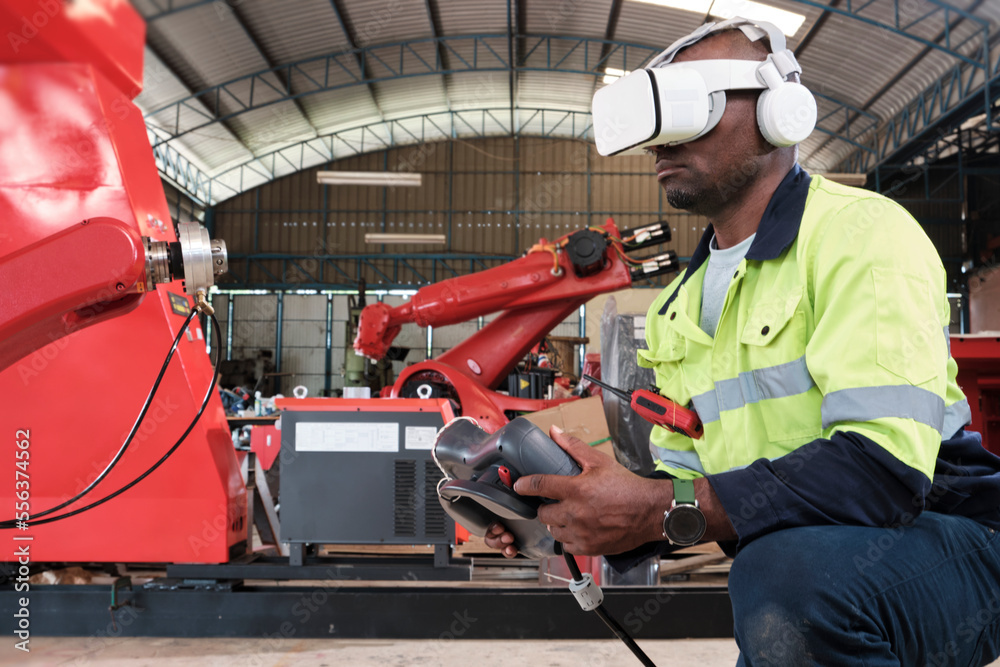 An African American engineer with VR glasses controls robotic arm, virtual simulator software in mechanical manufacturing factory, and intelligent automatic machines technology in industry innovation. An African American engineer with VR glasses controls robotic arm, virtual simulator software in mechanical manufacturing factory, and intelligent automatic machines technology in industry innovation.