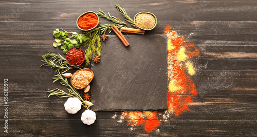 Fototapeta Naklejka Na Ścianę i Meble -  Different spices with empty slate plate on dark wooden background