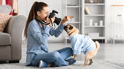 Teenage girl taking photo of cute pug dog at home