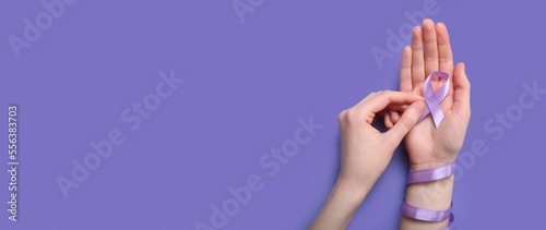 Leinwand Poster Female hands holding awareness ribbon on lilac background with space for text