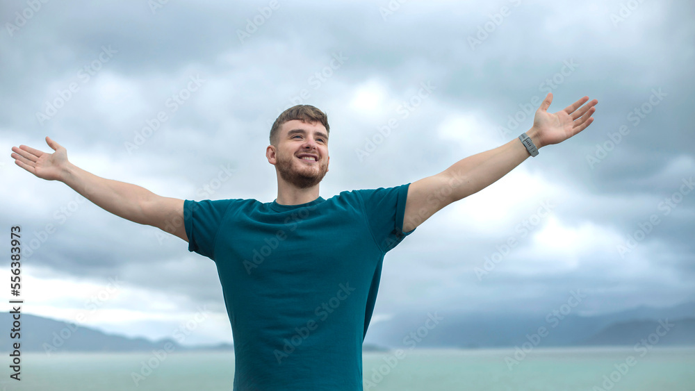 happy handsome free guy, young calm relaxed carefree man traveler with open raised hands enjoy sea, ocean view, person feeling good, breath deep deeply fresh air. Freedom, travel, happiness concept