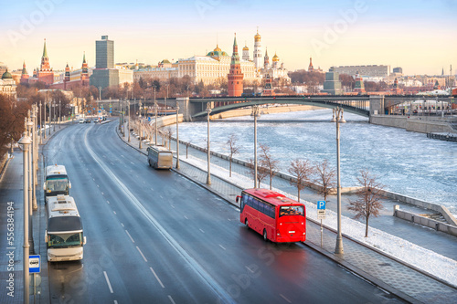 Red bus "Unforgettable Moscow" on the Prechistenskaya embankment of the Moscow River and a view of the Kremlin, Moscow © yulenochekk