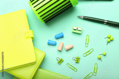 Different earplugs and stationery on color background