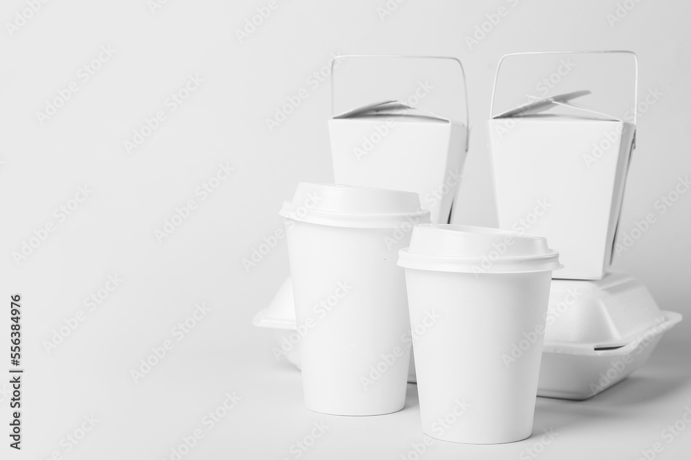 Paper cups and different food containers on light background Paper cups and different food containers on light background
