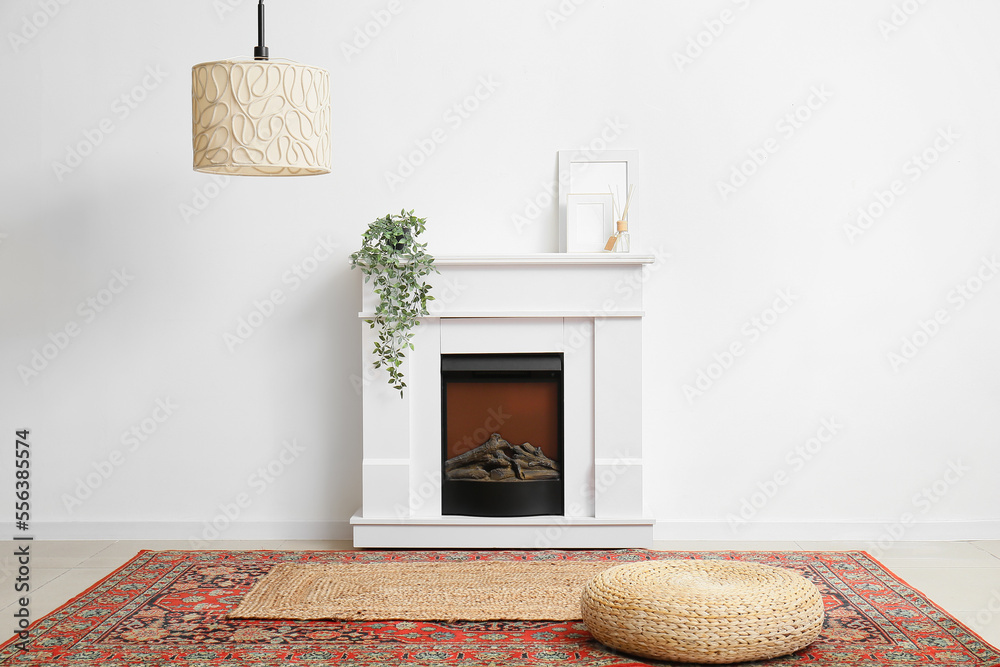 Interior of room with wicker pouf and fireplace near white wall - obrazy, fototapety, plakaty 