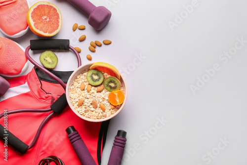 Fototapeta Naklejka Na Ścianę i Meble -  Sports clothes, shoes, equipment and bowl with healthy food on light background