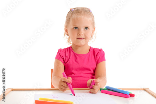Cute little girl drawing with felt-tip pens at table on white background