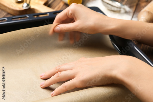 Woman putting paper into baking sheet  closeup