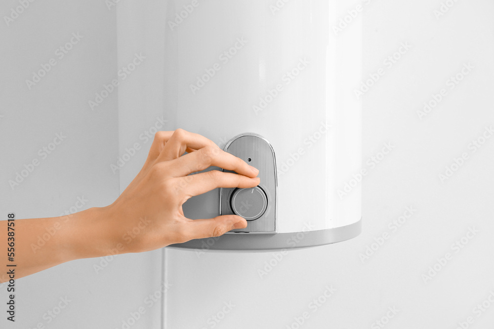 Woman adjusting boiler on light wall, closeup Woman adjusting boiler on light wall, closeup