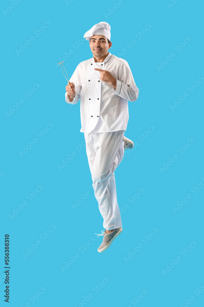 Young chef with masher jumping on blue background Young chef with masher jumping on blue background