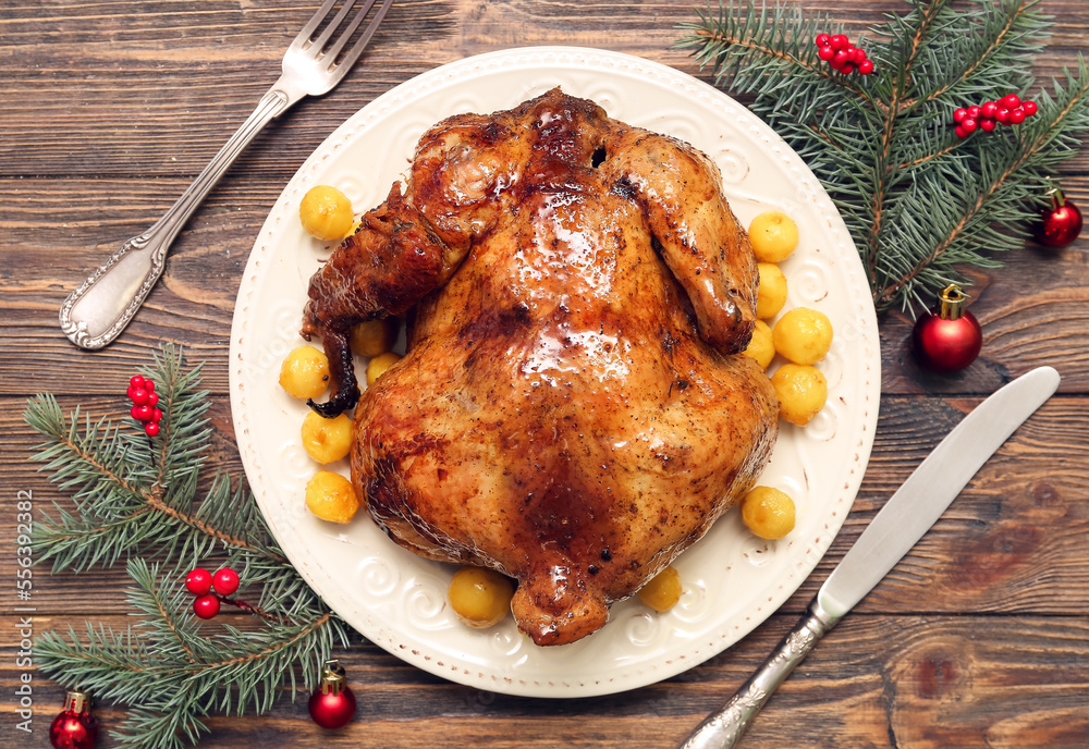 Composition with plate of tasty baked chicken, fir branches and Christmas decorations on wooden background Composition with plate of tasty baked chicken, fir branches and Christmas decorations on wooden background