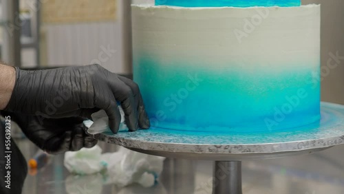 cake designer smoothing and levelling frosted grandient blue white wedding cake with spatula and scraper 4k footage photo