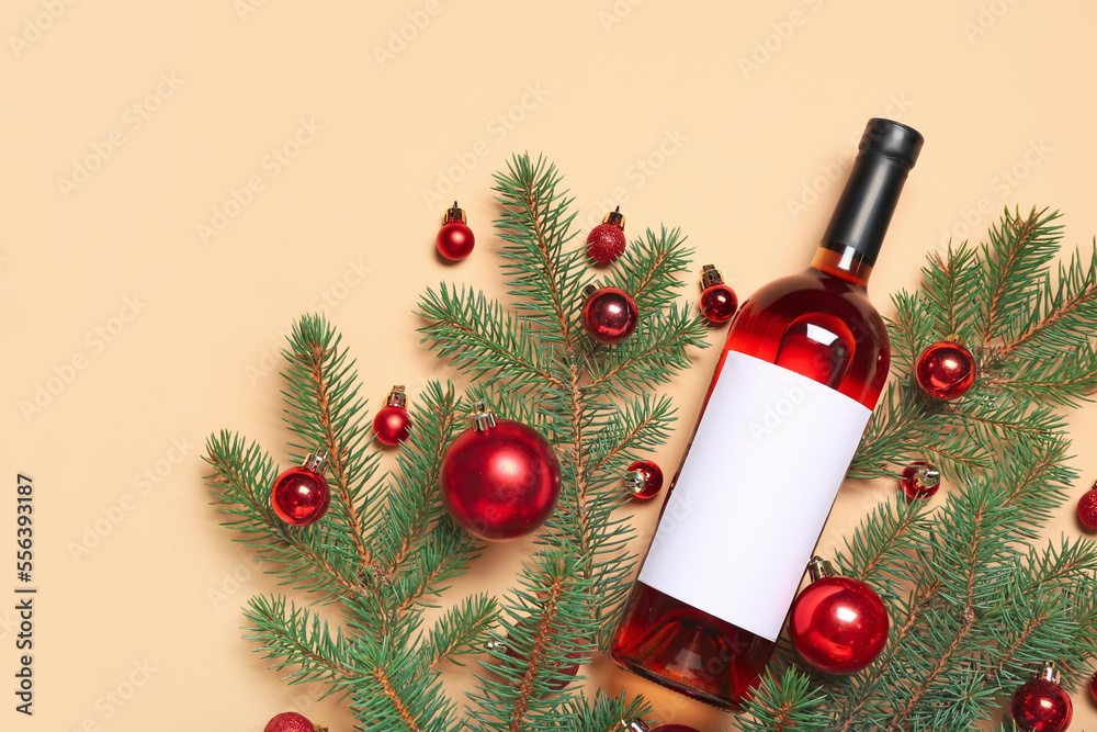 Bottle of wine with Christmas balls and fir branches on beige background