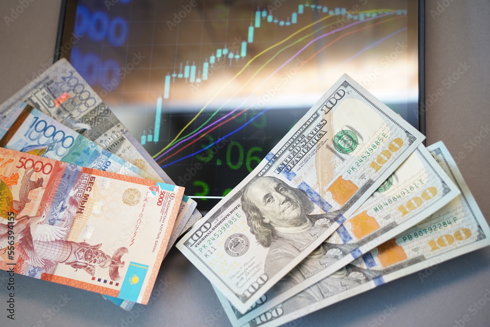 Almaty, Kazakhstan - 10.04.2022 : Stock charts on the tablet and tenge and dollar banknotes on the table. Almaty, Kazakhstan - 10.04.2022 : Stock charts on the tablet and tenge and dollar banknotes on the table.