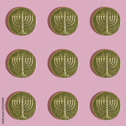 Seamless pattern with Hanukkah gelt chocolate coins on pink background.
