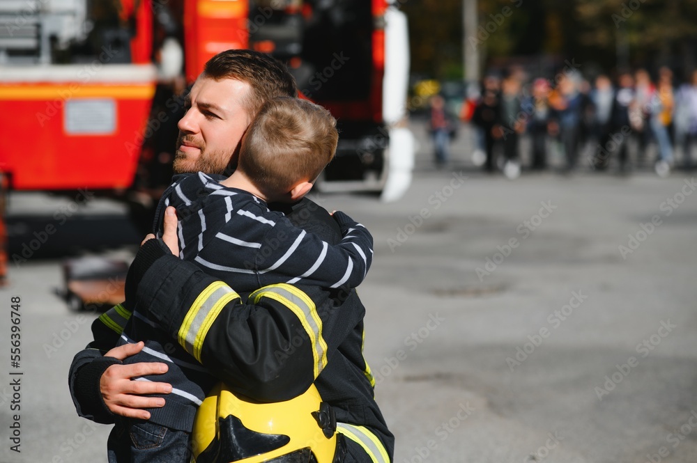 Portrait of rescued little boy with firefighter man standing near fire ...