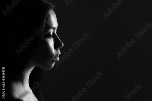 High contrast black and white female portrait of a beautiful girl on a black background.