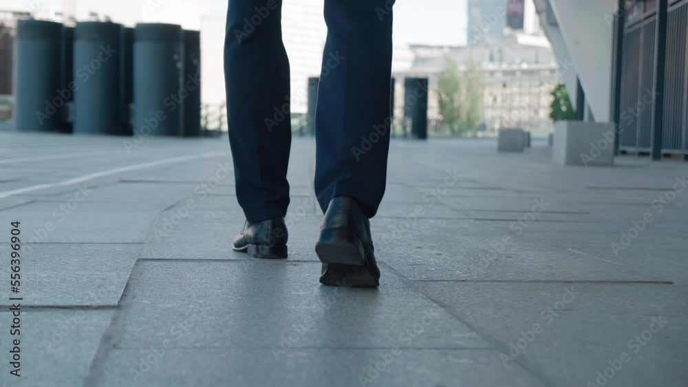 Rear view confident gait of man entrepreneur walking from work. Close up feet of confident entrepreneur man in leather shoes walking around the city in the business district. Business concept. Rear view confident gait of man entrepreneur walking from work. Close up feet of confident entrepreneur man in leather shoes walking around the city in the business district. Business concept.