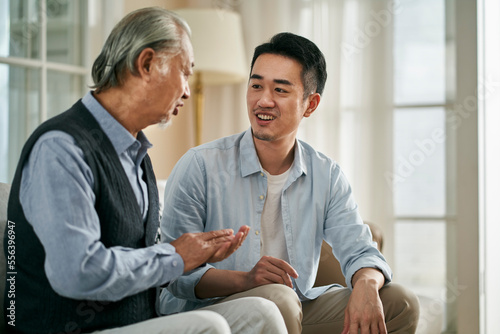 asian elderly father and adult son chatting at home