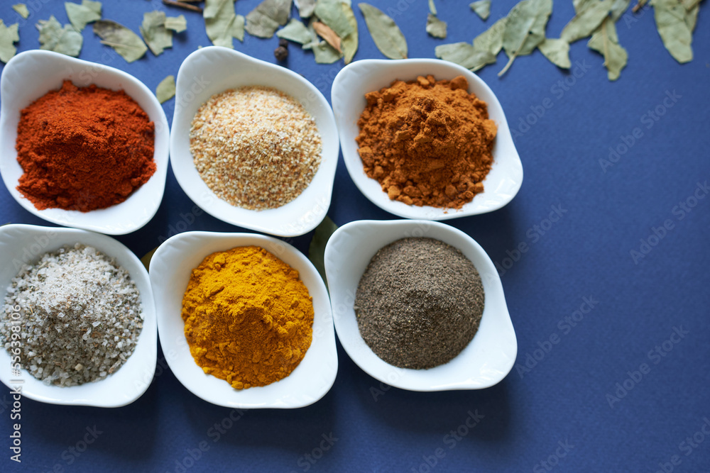 Different kinds of spices on a blue background. Dried garlic and three types of peppers. Different kinds of spices on a blue background. Dried garlic and three types of peppers.